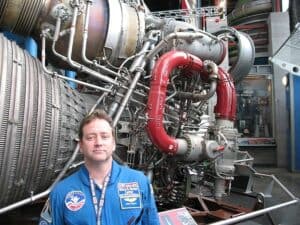 Tour guide stands before an F-1 rocket engine