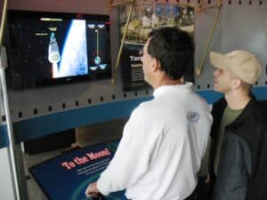 A couple of visitors try their hand at steering a Saturn rocket through space.