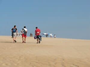 Three hang gliding students ascend a dune at Jockey Ridge State Park.